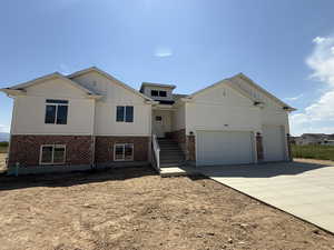 View of front of house featuring board and batten siding, driveway, brick siding, and a garage