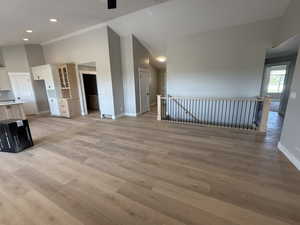 Unfurnished living room featuring light wood finished floors and high vaulted ceiling