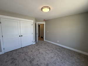 Unfurnished bedroom with a textured ceiling, carpet, and a closet