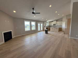 Unfurnished living room with recessed lighting, a fireplace, vaulted ceiling, ceiling fan, and light wood finished floors