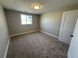 Spare room featuring light carpet and a textured ceiling