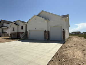 View of property exterior featuring driveway, board and batten siding, brick siding, and an attached garage