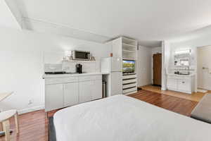 Bedroom featuring freestanding refrigerator and light wood-style flooring