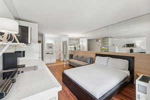 Bedroom featuring wood finished floors, heating unit, and connected bathroom