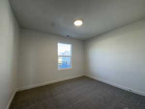 Unfurnished room featuring dark carpet and a textured ceiling