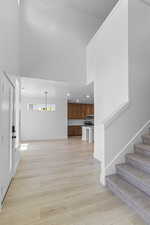 Unfurnished living room with a towering ceiling, light wood-type flooring, stairway, and recessed lighting