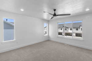 Empty room featuring healthy amount of natural light, carpet floors, a textured ceiling, ceiling fan, and recessed lighting