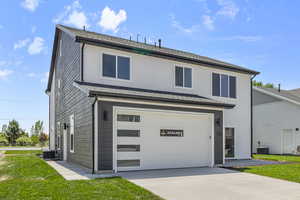 View of front of property with a garage, a front lawn, concrete driveway, and roof with shingles
