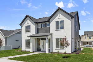 View of front of house featuring a front lawn, stucco siding, and roof with shingles