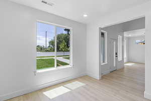 Empty room with healthy amount of natural light, light wood-style floors, and recessed lighting