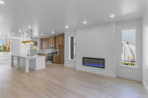 Kitchen with brown cabinets, a kitchen bar, an island with sink, recessed lighting, and pendant lighting