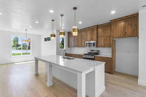 Kitchen with brown cabinetry, stainless steel appliances, a breakfast bar area, tasteful backsplash, and hanging light fixtures
