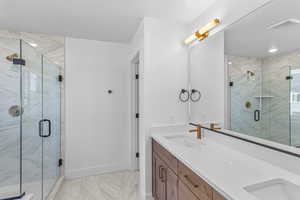 Bathroom featuring a marble finish shower, double vanity, and light marble finish flooring