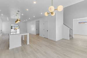 Kitchen with recessed lighting, hanging light fixtures, an island with sink, open floor plan, and light wood-style floors