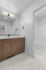 Bathroom featuring vanity, light marble finish floors, and  shower combination