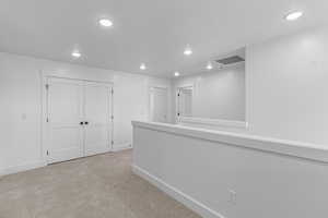 Hallway featuring light colored carpet and recessed lighting