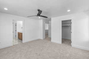 Unfurnished bedroom featuring a spacious closet, light carpet, recessed lighting, a ceiling fan, and connected bathroom