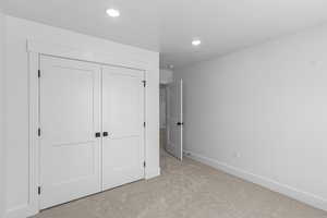 Unfurnished bedroom featuring light carpet, a closet, and recessed lighting