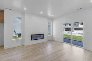 Unfurnished living room featuring recessed lighting, a glass covered fireplace, and light wood-type flooring