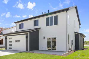 Back of property with a garage, stucco siding, and a lawn