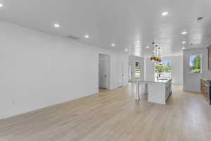 Kitchen featuring open floor plan, a breakfast bar, pendant lighting, a center island with sink, and recessed lighting
