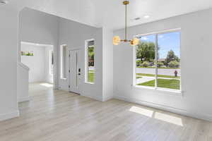 Foyer featuring plenty of natural light, a chandelier, and light wood-style flooring