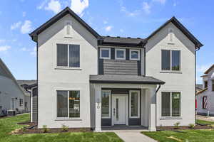 View of front of home with a front lawn, stucco siding, and roof with shingles