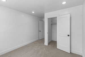 Unfurnished bedroom featuring light colored carpet, a walk in closet, and recessed lighting