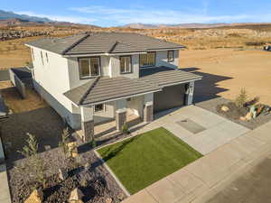 View of front facade with covered porch, a tile roof, a mountain view, stone siding, and concrete driveway