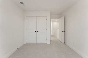 Unfurnished bedroom featuring light colored carpet and a closet