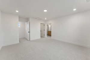 Unfurnished bedroom featuring recessed lighting, light colored carpet, and ensuite bathroom