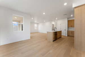 Kitchen featuring recessed lighting, decorative backsplash, a center island with sink, light wood-style flooring, and open floor plan