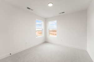 Empty room featuring light colored carpet and baseboards