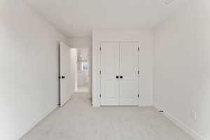 Unfurnished bedroom with light colored carpet and a closet