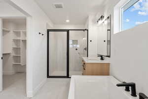 Full bathroom with a stall shower, a bath, vanity, and a spacious closet
