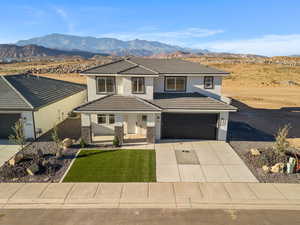 View of front facade featuring a porch, stucco siding, concrete driveway, a mountain view, and a front lawn