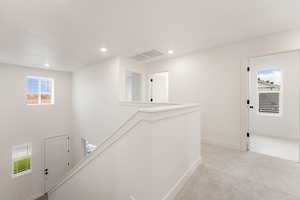 Hall with an upstairs landing, light carpet, and recessed lighting