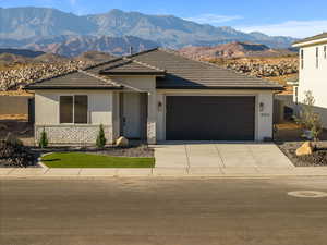 View of front of house with stone siding, a mountain view, stucco siding, and concrete driveway