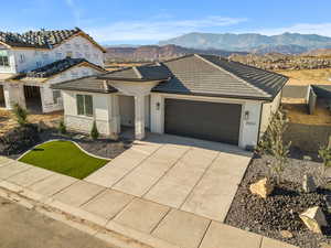 View of front of house featuring stucco siding, an attached garage, concrete driveway, a mountain view, and brick siding