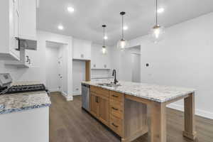 Kitchen featuring light stone counters, dark wood finished floors, stainless steel appliances, decorative light fixtures, and recessed lighting