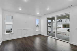 Unfurnished room with dark wood-style floors, a decorative wall, wainscoting, and recessed lighting
