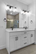 Full bathroom featuring double vanity, light tile patterned floors, and a stall shower