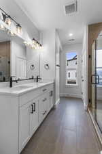 Full bathroom featuring double vanity, a stall shower, and light tile patterned flooring