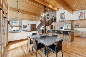Dining space featuring stairway, high vaulted ceiling, light wood finished floors, a wood ceiling with exposed beams, and a ceiling fan