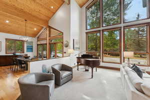 Living room with high vaulted ceiling, a wooden ceiling with exposed beams, a chandelier, recessed lighting, and light wood-style flooring