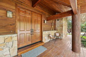 View of exterior entry featuring stone siding and a wooden deck
