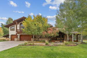 View of front of house featuring stone siding, a front lawn, a garage, and driveway
