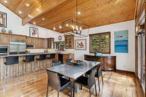 Dining room featuring light wood-style floors, a wood ceiling with exposed beams, recessed lighting, high vaulted ceiling, and a chandelier