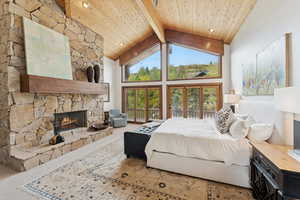 Carpeted bedroom featuring high vaulted ceiling, a fireplace, and a wooden ceiling with exposed beams