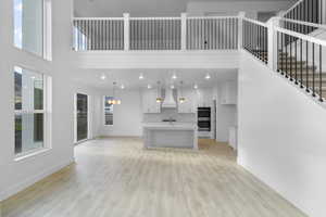 Living room with a towering ceiling, light wood finished floors, recessed lighting, and a chandelier in dining